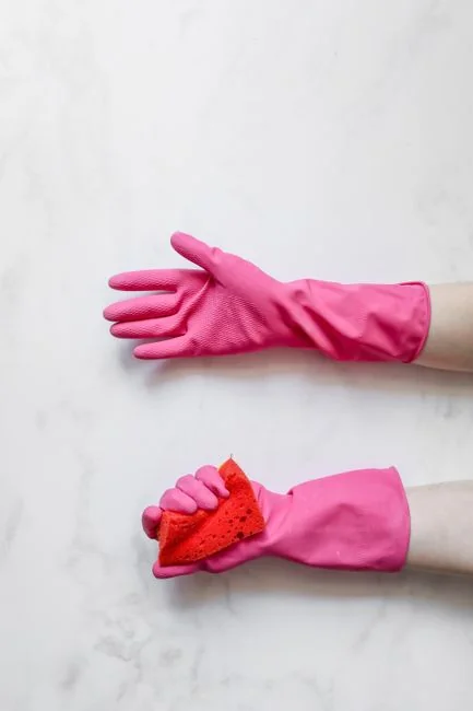 Close-up of a person disinfecting a remote control wearing protective gloves, ensuring cleanliness.